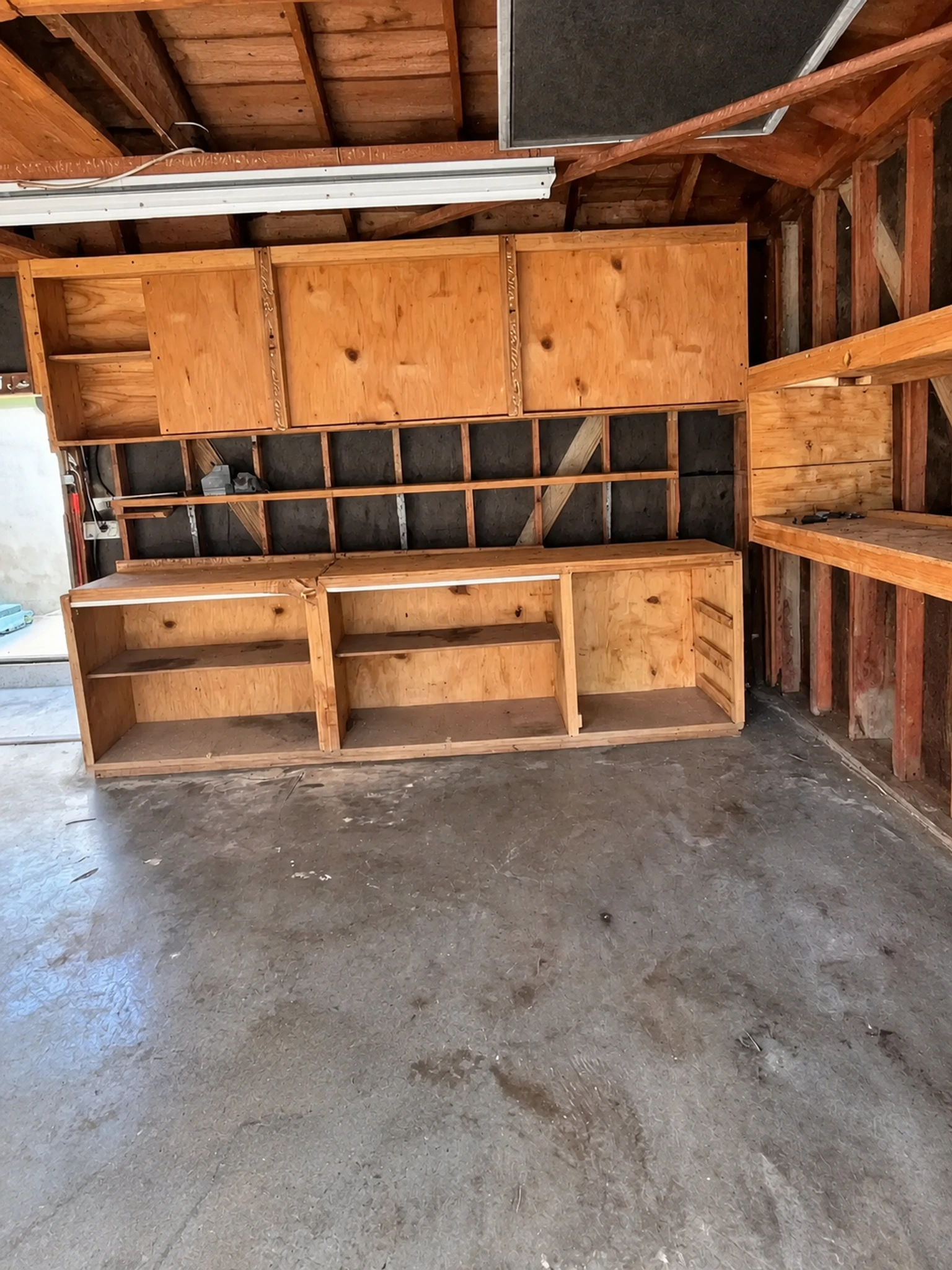 Garage conversion ADU — the original garage before conversion, exposed rafters and old shelving, Brea, Avorino