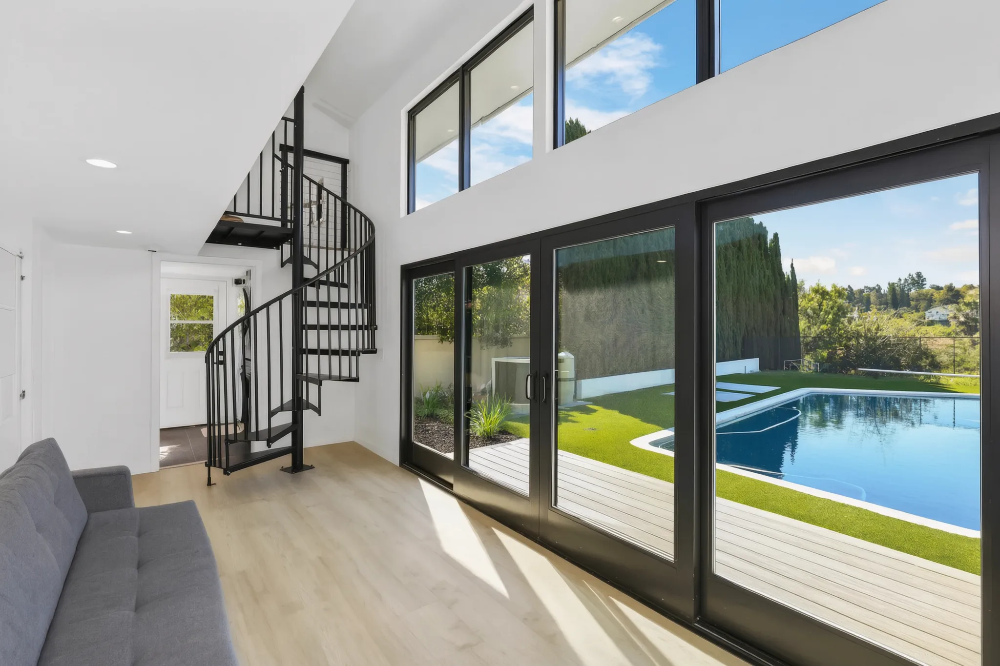 Two-story detached ADU — living room, spiral stair and sliders open to the pool, Santa Ana Hills, Avorino