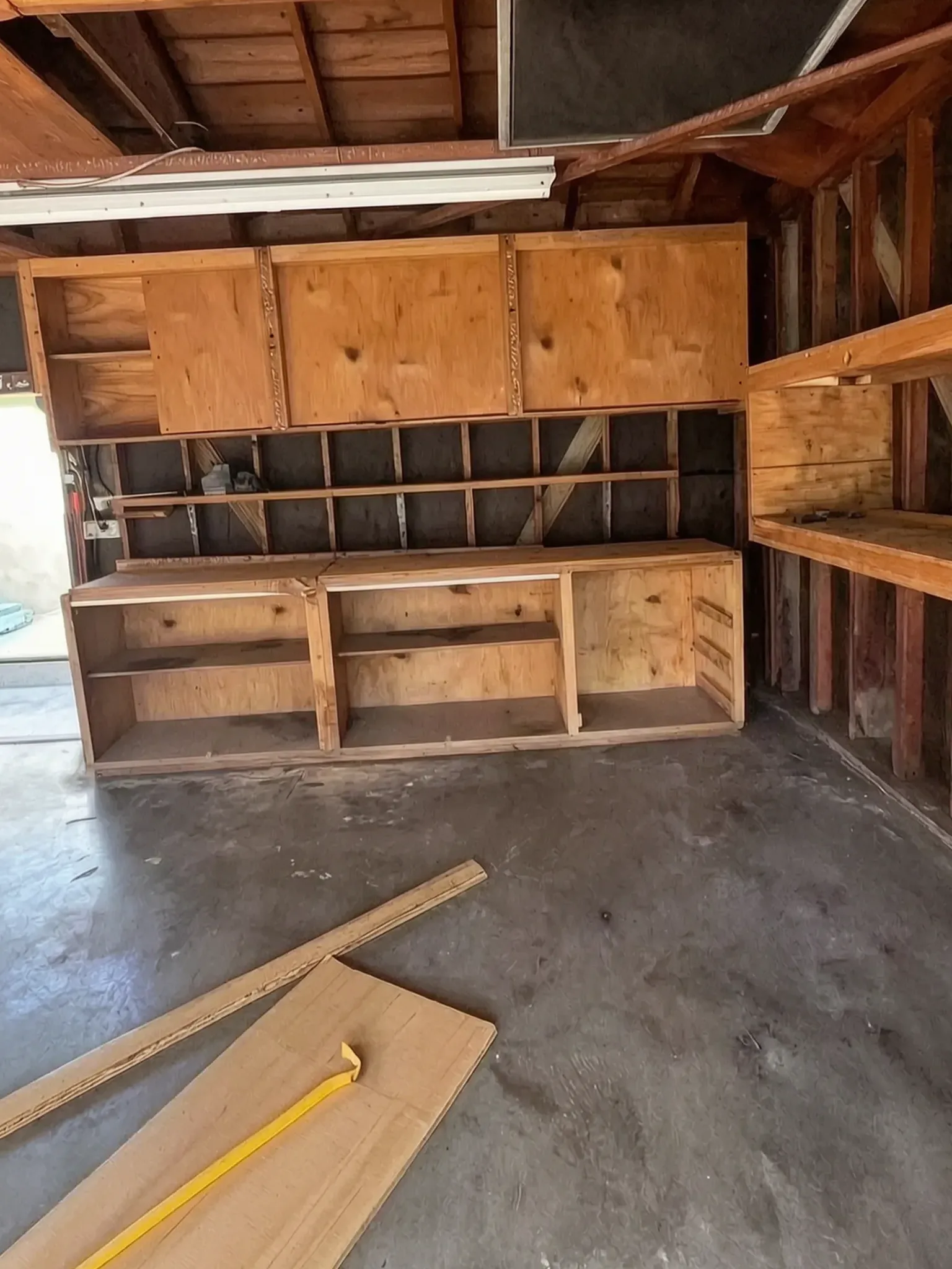 Garage conversion ADU — the original garage before conversion, exposed rafters and old shelving, Brea, Avorino