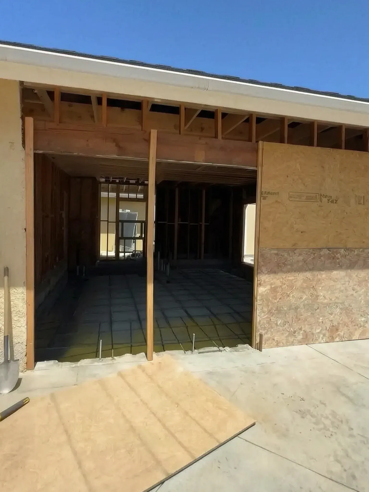 Garage conversion ADU under construction — garage opening stripped to studs with new sheathing, Brea, Avorino