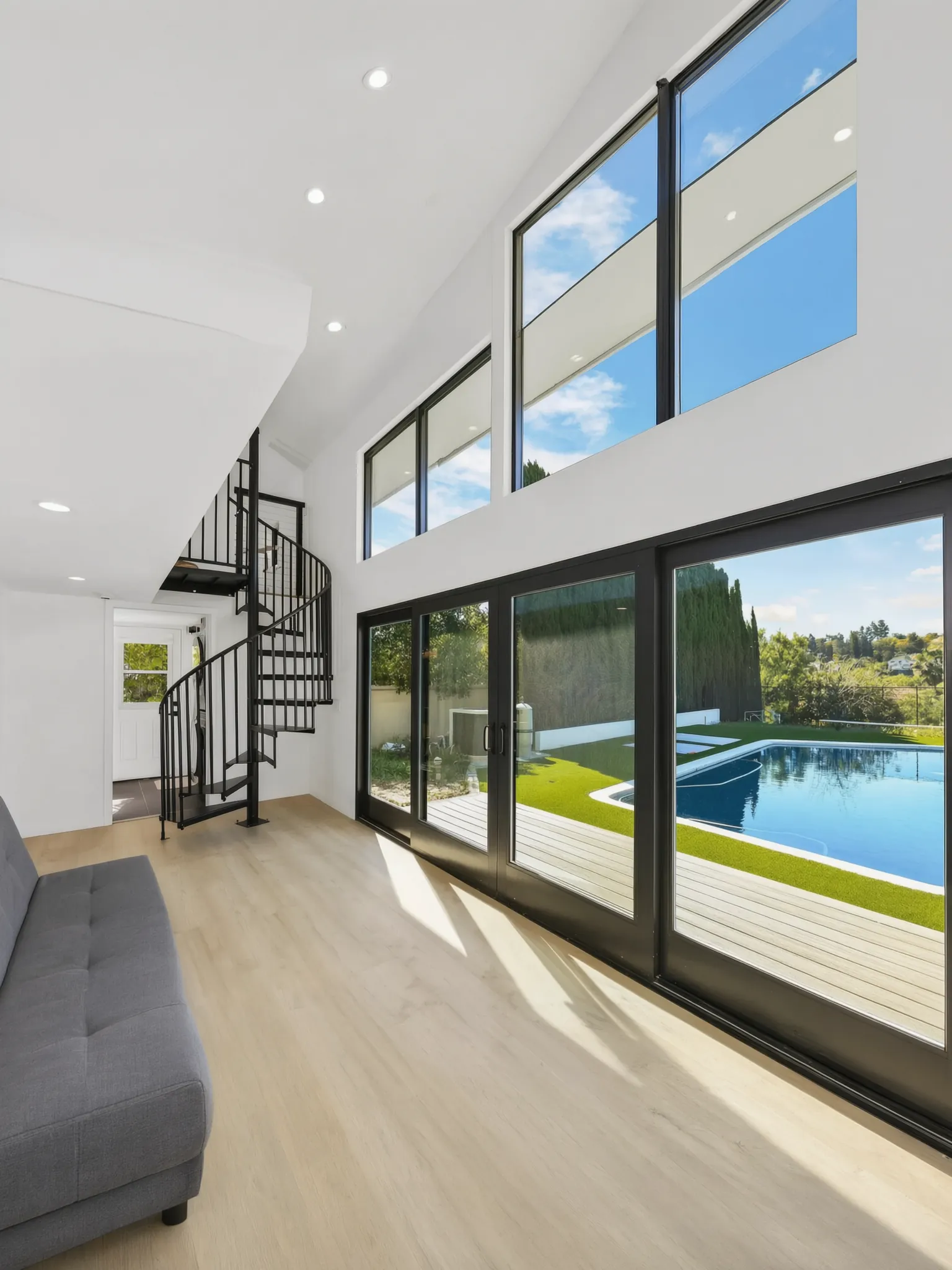 Inside an Avorino two-story detached ADU in Santa Ana Hills: a spiral stair and a glass wall onto the pool