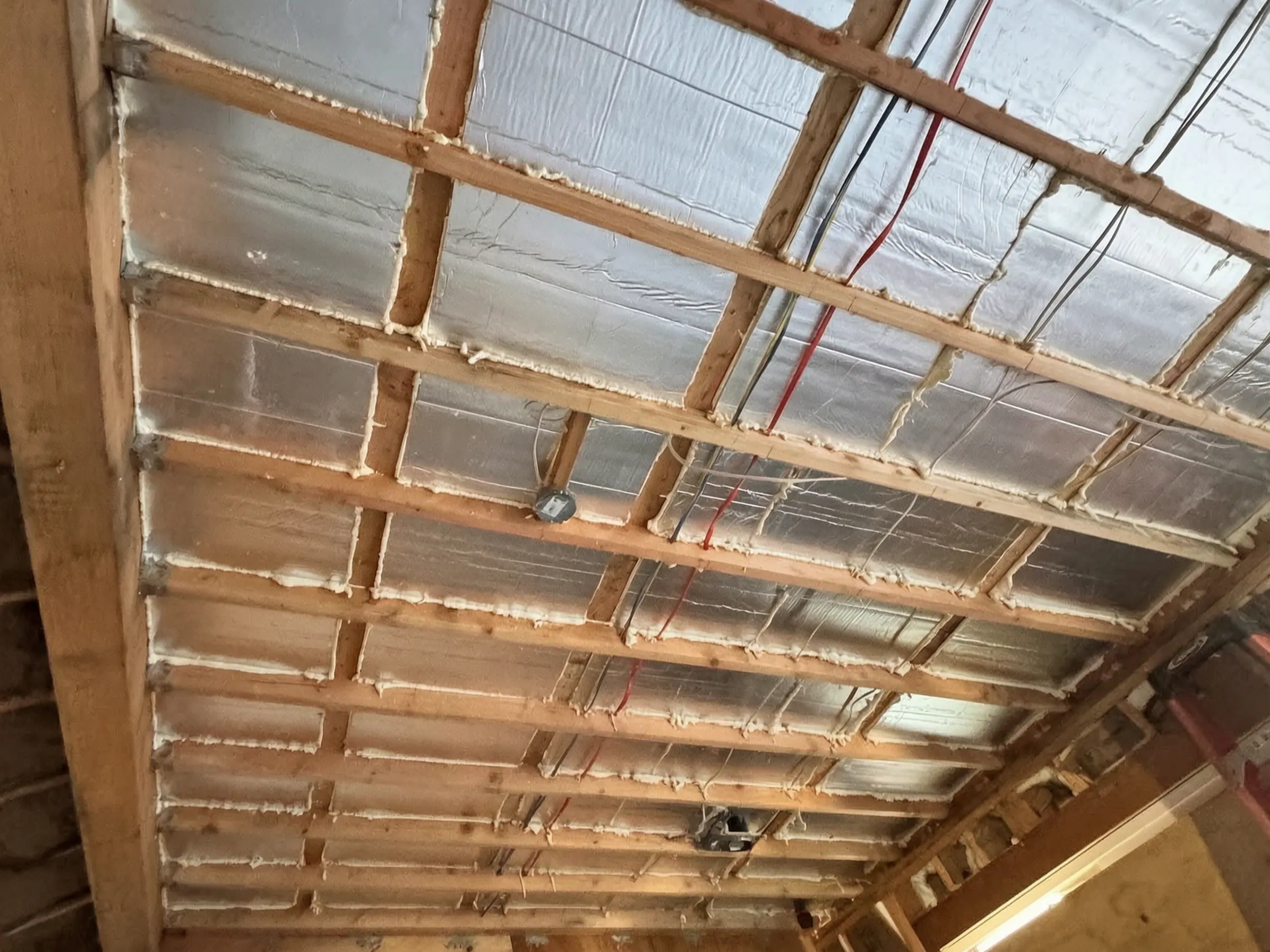 The ceiling insulated between the joists, with the rough-in runs in place. New construction in Santa Ana, built by Avorino.